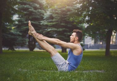 Genç adam pratik Yoga tekne poz açık havada