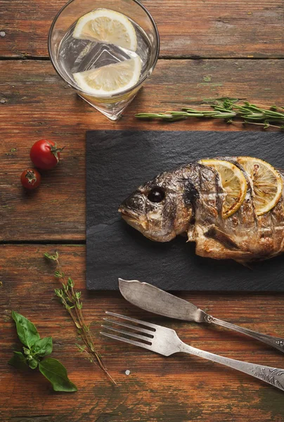 Whole grilled dorado with lemon slices on wood — Stock Photo, Image