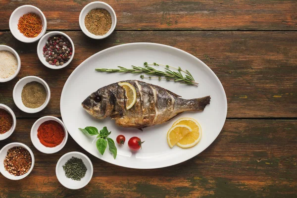 Whole grilled dorado with lemon slices on table — Stock Photo, Image