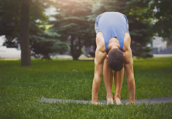 Sporty man doing Standing Forward Bend outdoors — Stock Photo, Image