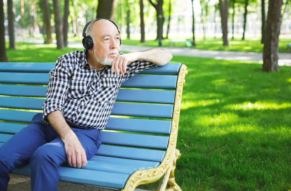 Hombre mayor pensativo en auriculares al aire libre — Foto de Stock