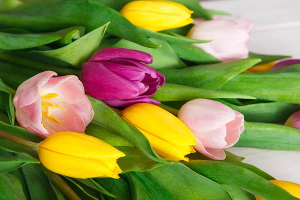 Buquê de tulipas brilhantes no fundo de madeira branca, espaço de cópia — Fotografia de Stock
