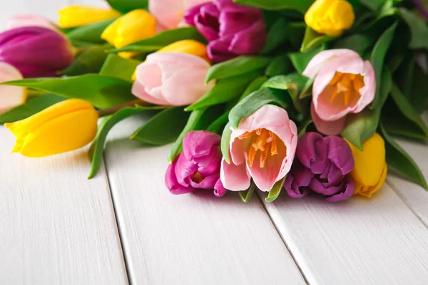 Buquê de tulipas brilhantes no fundo de madeira branca, espaço de cópia — Fotografia de Stock