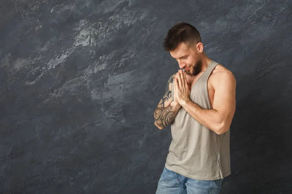 Knappe jongeman bidden op grijze achtergrond — Stockfoto