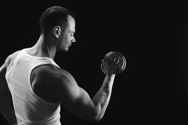 Hombre atlético fuerte con mancuerna muestra el cuerpo muscular —  Fotos de Stock