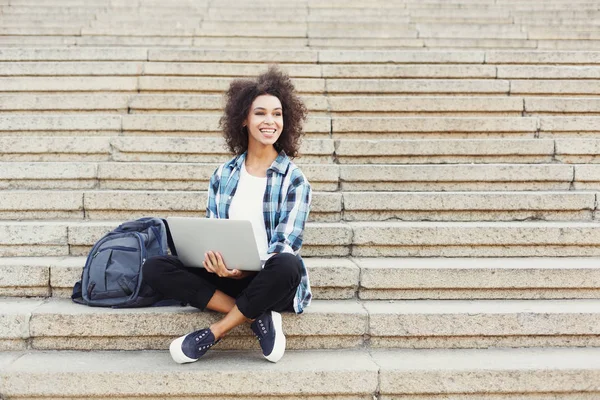 Leende student sitter på trappan med laptop — Stockfoto
