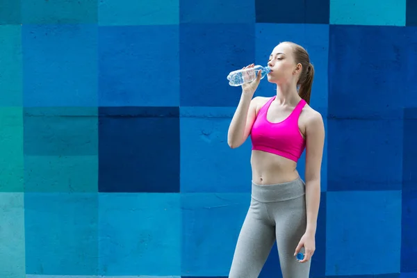 La corredora está descansando, bebiendo agua. — Foto de Stock
