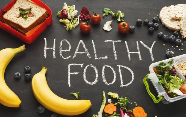 Lunch boxes filled with healthy food on black board — Stock Photo, Image