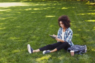 Parkta akıllı telefon kullanan genç kadın.