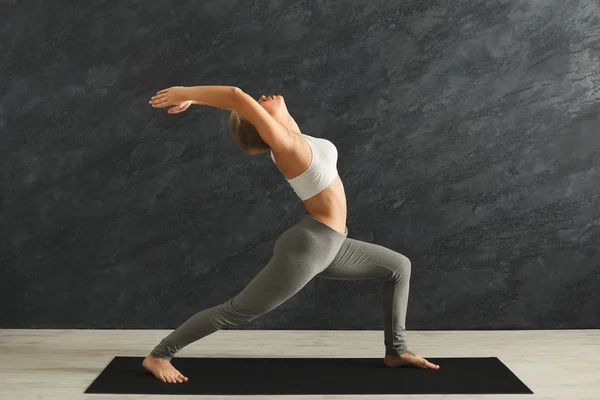 Mulher treinando ioga em pose de herói no ginásio — Fotografia de Stock