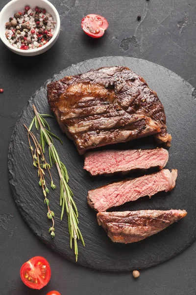 Rib eye steak en specerijen op zwarte achtergrond — Stockfoto