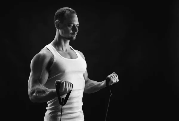 Atletico muscolare uomo esercizio con elastico espansore a nero — Foto Stock