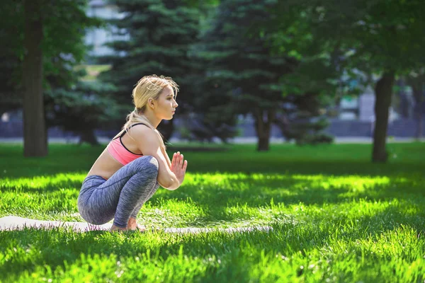 Woman training yoga in Regular Squat Pose .