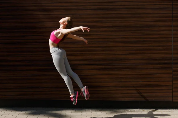 Hermosa mujer joven saltando contra la pared de madera — Foto de Stock