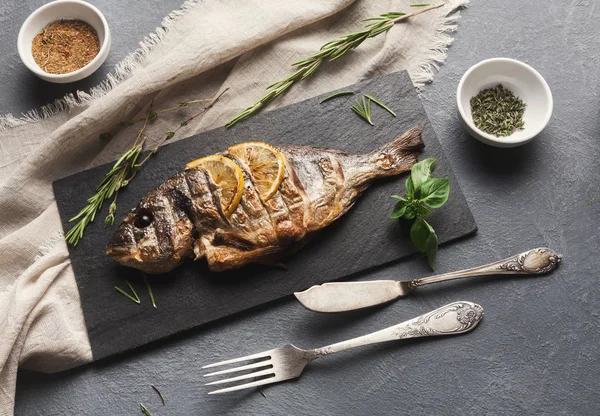 Whole grilled dorado with lemon slices on table — Stock Photo, Image