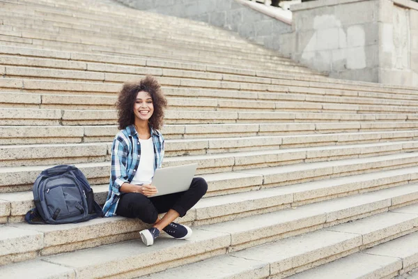 Usmívající se student sedí na schodech pomocí přenosného počítače — Stock fotografie