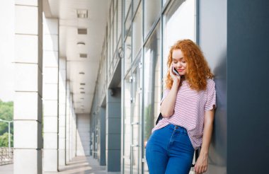Üzerinde telefon açık havada bir genç Kızıl saçlı kadın