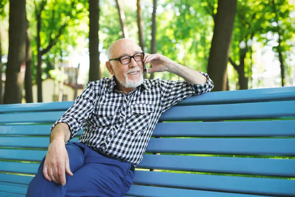 Sorrindo homem sênior em casual falando no móvel ao ar livre — Fotografia de Stock