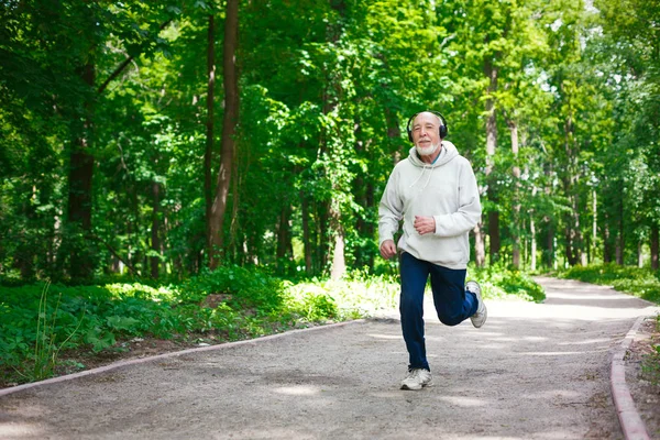 Пожилой человек бегает в зеленом лесу, копирует пространство — стоковое фото