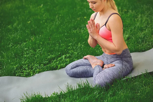 Joven mujer atractiva practicando yoga sentada en padmasana — Foto de Stock