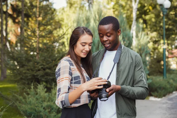 Pareja multiétnica viendo fotos en la cámara — Foto de Stock