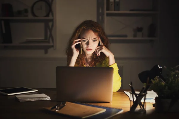 Donna sconvolta che parla al telefono mentre lavora sul computer portatile — Foto Stock