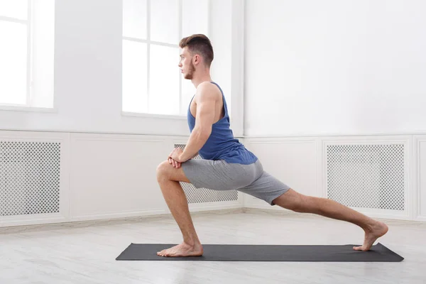 Hombre estirándose en el fondo blanco en interiores — Foto de Stock