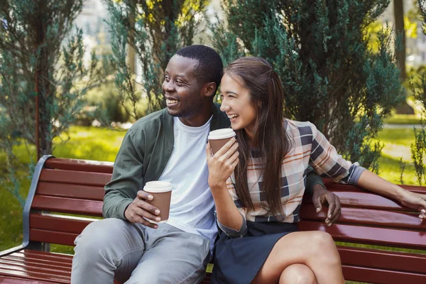 Casal multiétnico apaixonado tomando café no parque — Fotografia de Stock