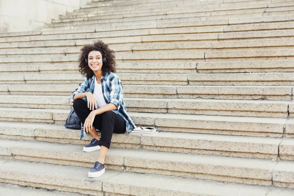 Ung flicka Lyssna på musik på universitet trappor — Stockfoto