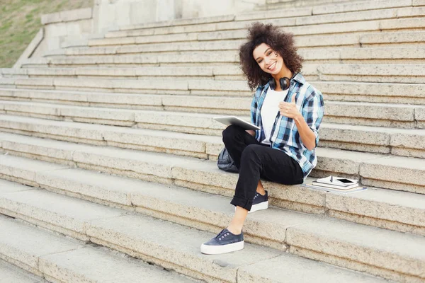 Leende student sitter på trappan med surfplatta — Stockfoto