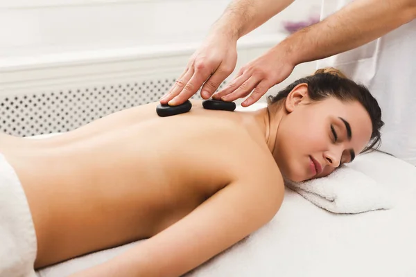 Frau lässt sich im Wellness-Salon mit heißen Steinen massieren — Stockfoto