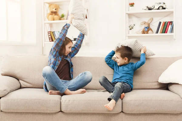 Brother and sister having pillow fight on sofa — Stock Photo, Image