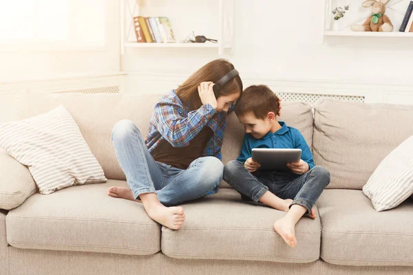 Двое детей слушают музыку дома на диване — стоковое фото