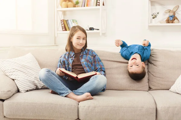 Молодая девушка читает книгу для своего брата — стоковое фото