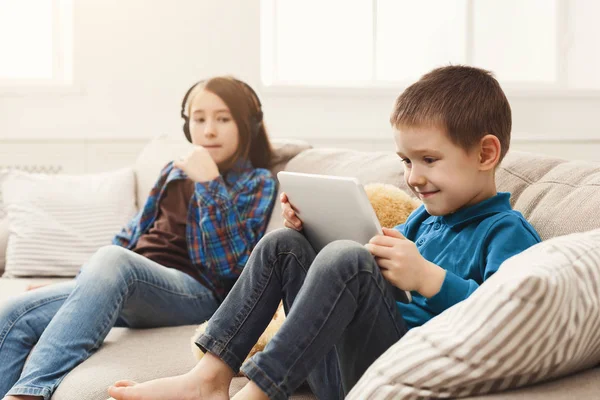 Dos niños con gadgets en el sofá en casa — Foto de Stock