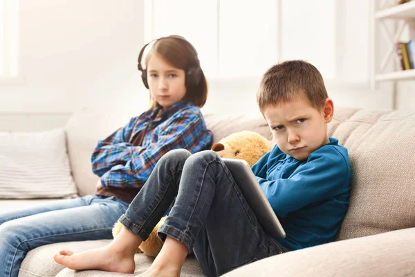 Dos niños con gadgets en el sofá en casa — Foto de Stock