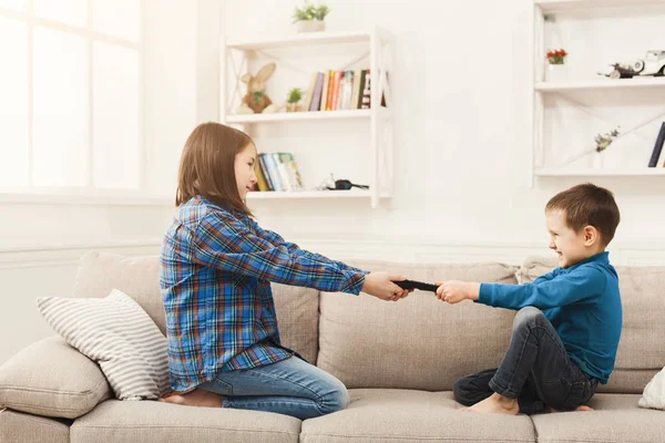 Siblings fighting over remote control at home — Stock Photo, Image