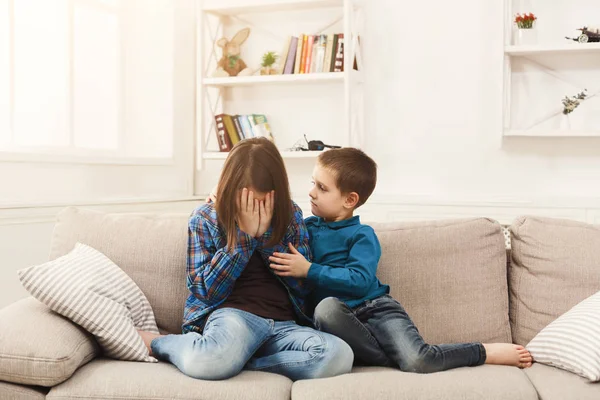 Мальчик обнимает плачущую сестру дома — стоковое фото