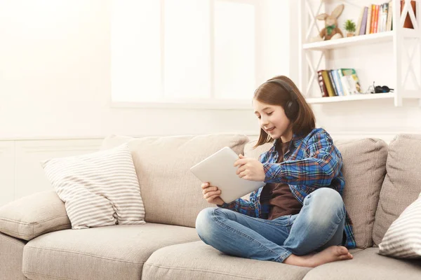 Little girl using digital tablet on sofa at home — Stock Photo, Image