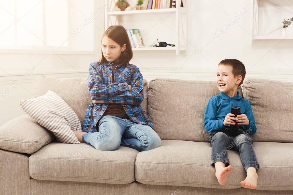 Two kids with remote control on couch at home