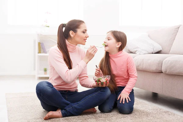 Klein meisje en haar moeder een salade eten thuis — Stockfoto