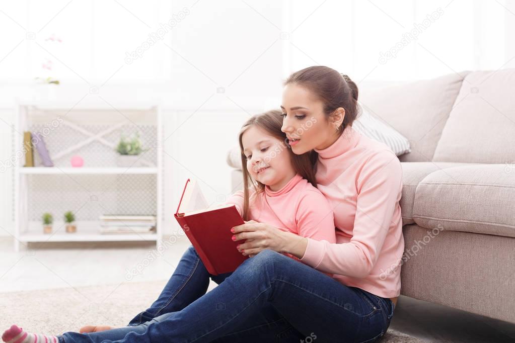 Little girl and her mom reading book at home
