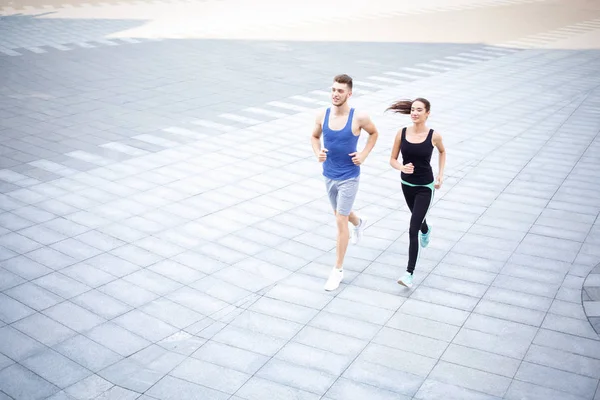 Young woman and man running in city copy space — Stock Photo, Image