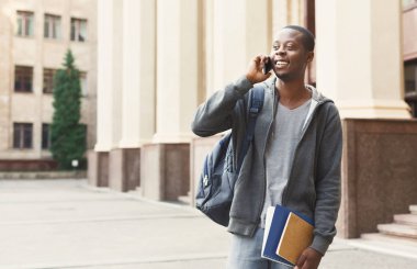 Kampüs içinde smartphone cep telefonu ile konuşmak mutlu Afrikalı-Amerikalı öğrenci