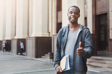 Afrikalı-Amerikalı öğrenci üniversite kampüsü içinde defter ile oturan
