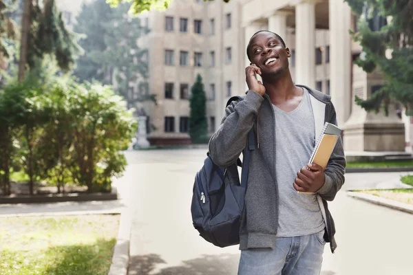 Feliz estudiante afroamericano hablando en un smartphone en el campus — Foto de Stock
