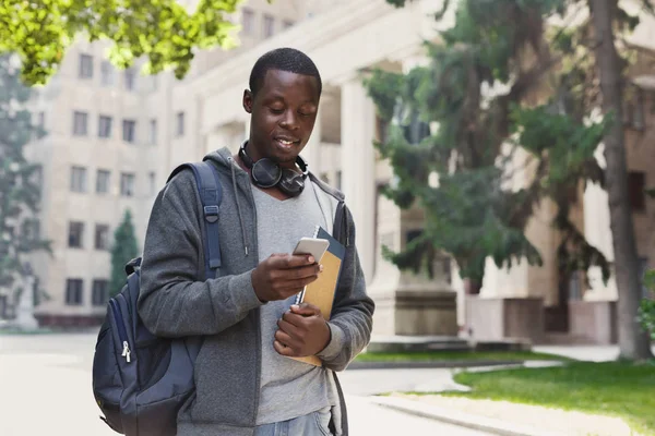 Счастливый африканско-американский студент пишет смс в университетском городке — стоковое фото