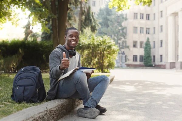 Estudiante afroamericano sentado con cuaderno en campus universitario — Foto de Stock