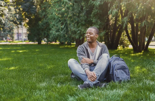 Feliz estudiante afroamericano sentado en el campus universitario al aire libre —  Fotos de Stock