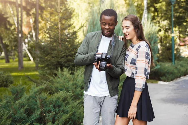 Pareja multiétnica viendo fotos en la cámara —  Fotos de Stock